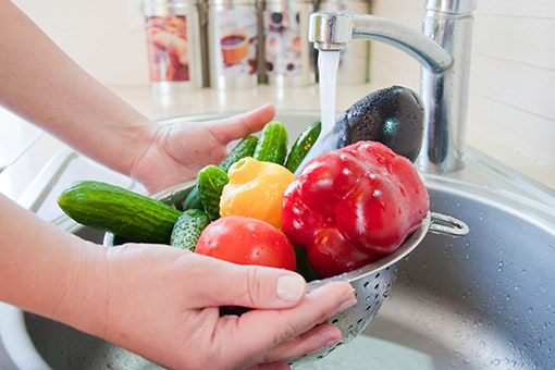Washing vegetables in a kitchen Washing vegetables under a tap