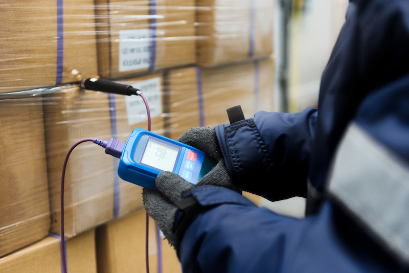 person reading a digital thermometer of warehouse stock